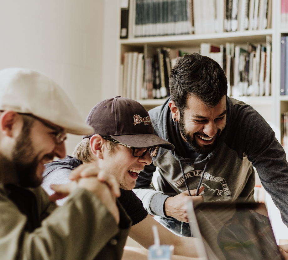 Group of co-workers sitting around a laptop, smiling