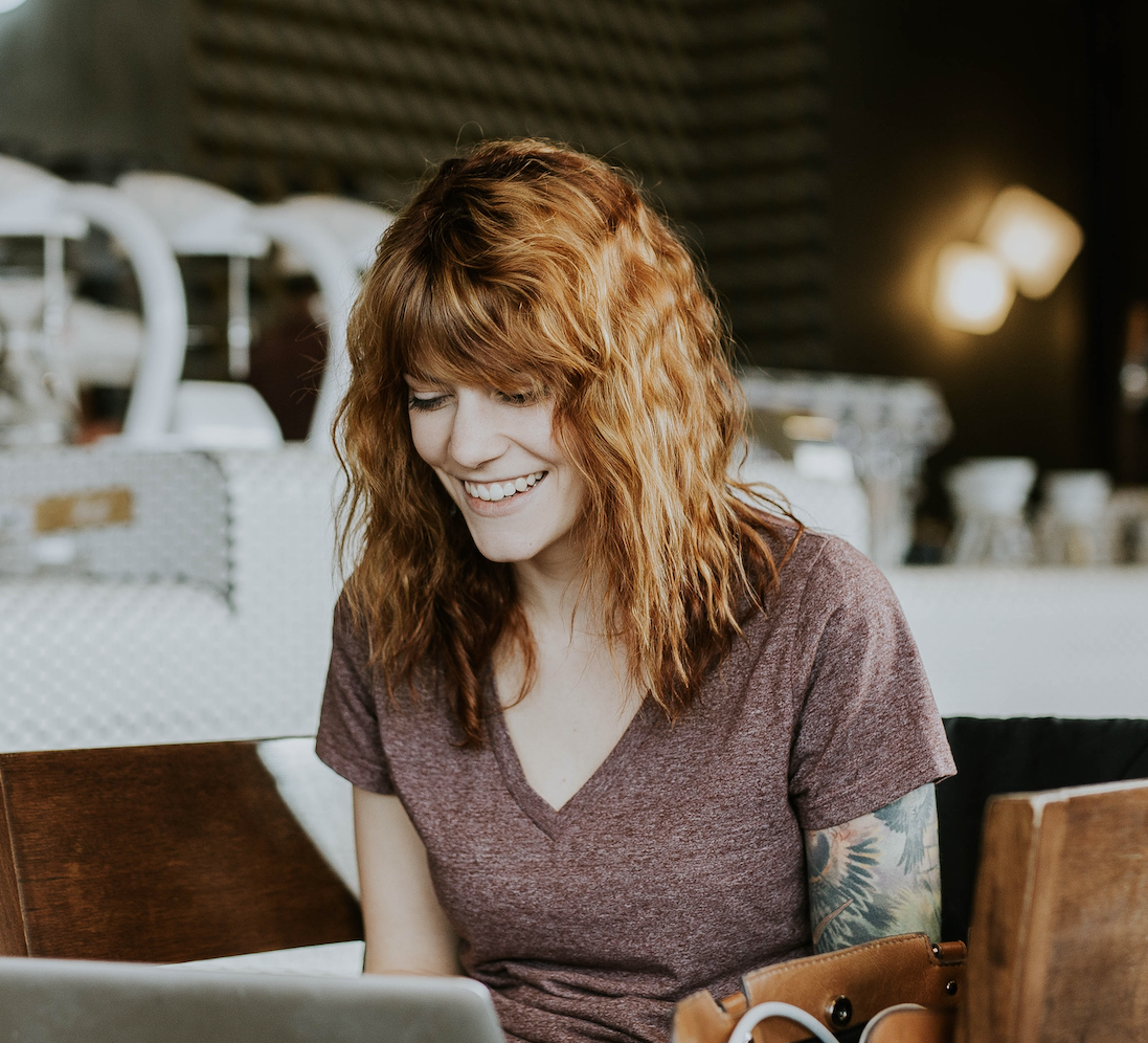 women sitting in front of laptop, smiling